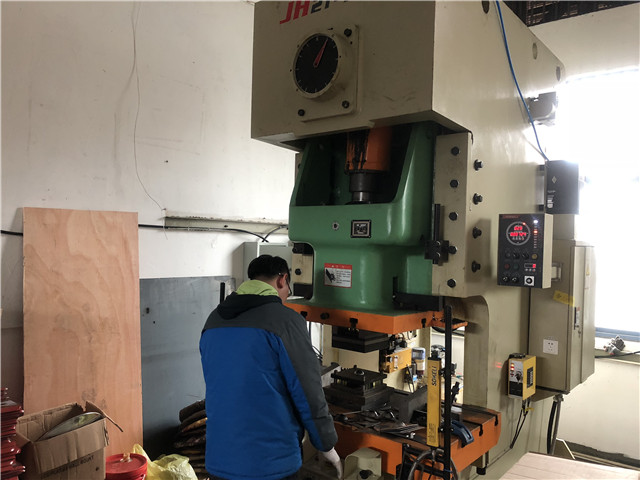 Workers work on punching machine for TV bracket