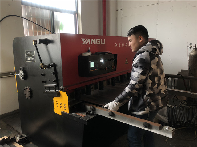 Workers work on shearing machine for TV bracket